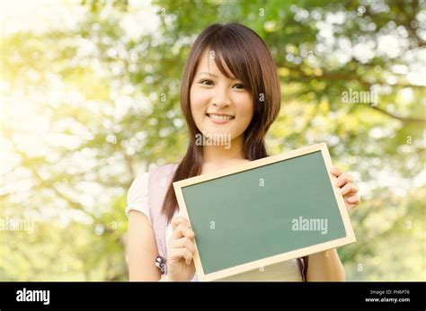 Young Asian College Girl Student Standing On Campus Lawn Holding A