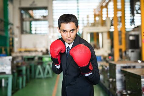 Asian Businessman With Boxing Gloves In Factory Ready To Fight Stock