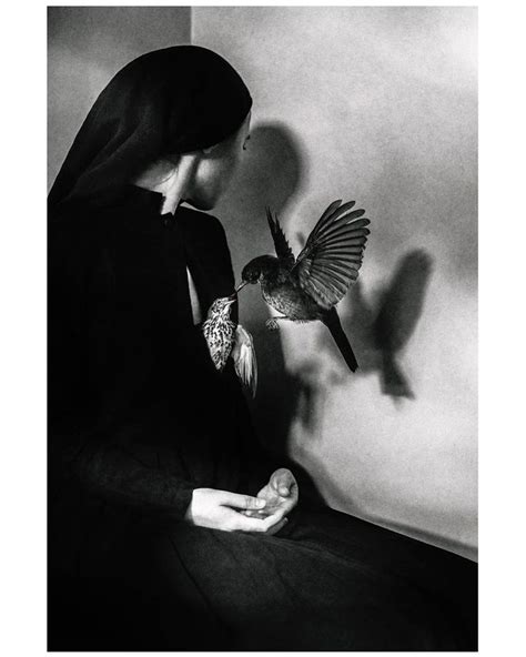 A Black And White Photo Of A Woman With A Bird In Her Hand Looking At