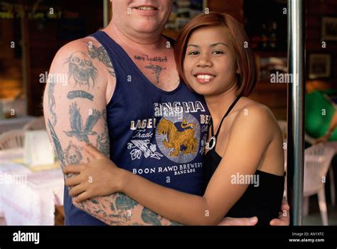 La Thaïlande Pattaya Bar Girl Hugging Tatoué Homme Touriste Qui Porte Des Tshirt Avec Le Logo