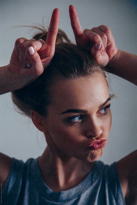 Young Blonde Woman Making Faces And Horns by Danil Nevsky