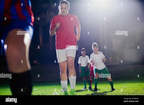 Young Female Soccer Players Practicing Agility Sports Drill On Field At