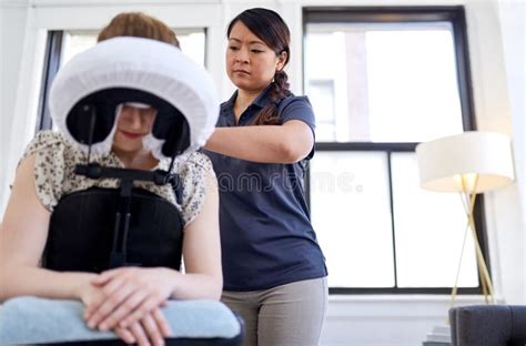 Chinese Woman Massage Therapist Giving A Neck And Back Pressure Treatment To An Attractive Blond