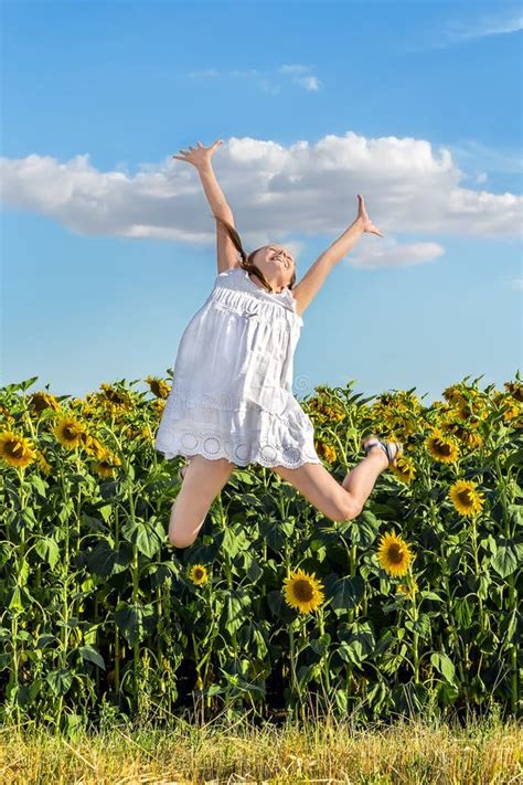 Girl Jumping On A Background Of A Field Of Sunflowers Stock Photo