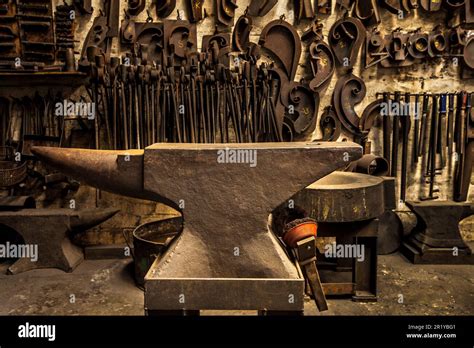 Workshop, metal tools and anvil in forge with wall background for