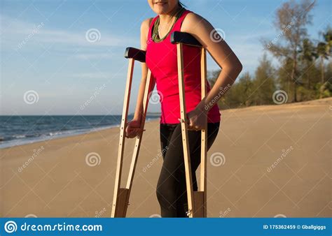 Patient Woman Using Crutches Support Broken Legs For Walking Beach