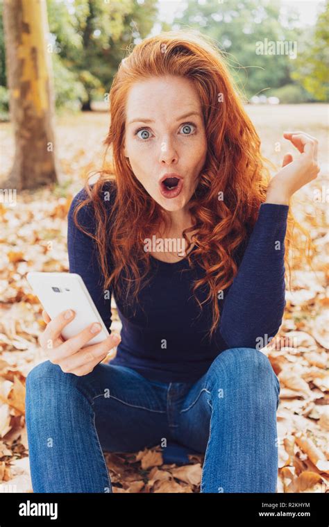 Shocked Young Redhead Woman Staring Wide Eyed At The Camera Making A