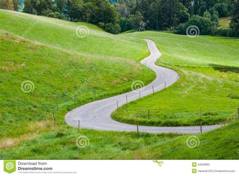 An Idyllic Road Between Green Fields In The Mountains Stock Image