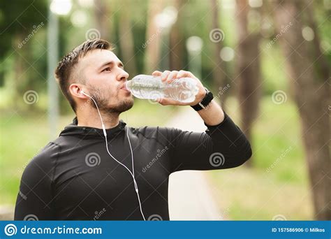 Athletic Man Drinking Water After Workout In The Park Stock Photo
