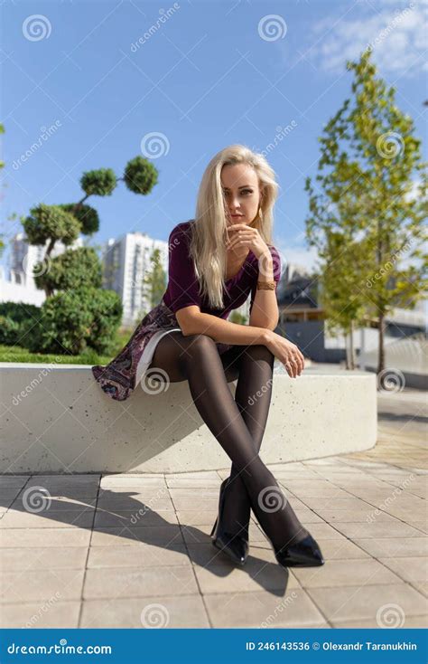 Blonde Woman With Perfect Legs In Pantyhose And Shoes With High Heels Posing At The City Square