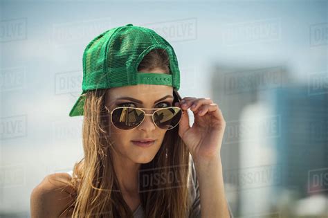 Caucasian Woman Wearing Baseball Cap Peering Over Sunglasses Stock