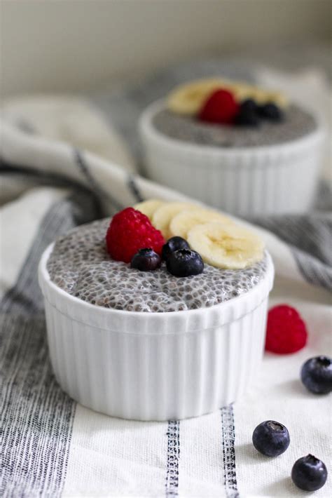 Two Small White Bowls Filled With Chia Pudding Topped With Berries And