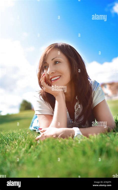 positive emotion adult woman relaxed lying on green grass in an outdoor park girl in