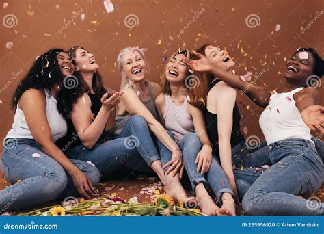 Group Of Six Laughing Women Of Different Ages Sitting Under Falling