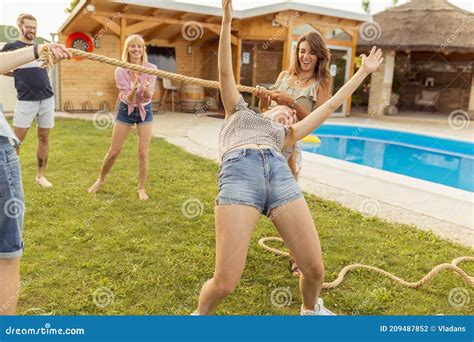 Friends Having Fun Doing Limbo Dance At Summer Party By The Pool Stock