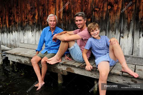 garçon assis avec grand père et père ensemble sur la jetée en été — loisirs bermudas shorts