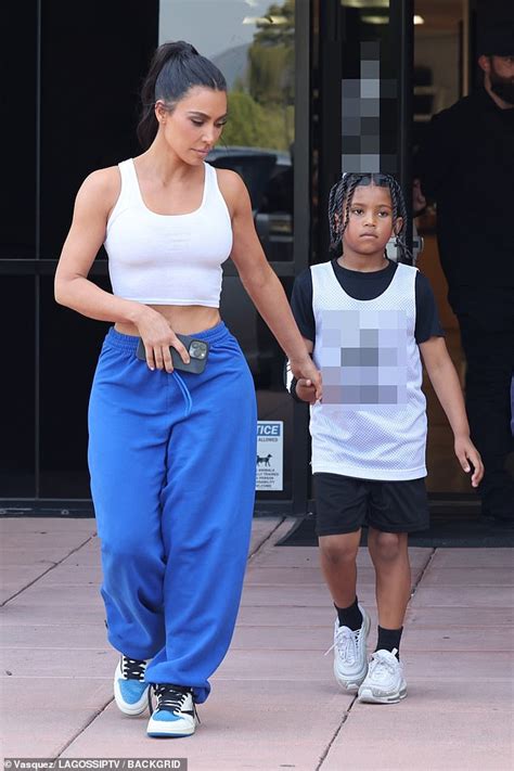 kim kardashian exhibits off tiny waist in crop prime and sweats as she holds arms with son saint