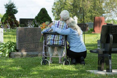 Caucasian Mother And Daughter Visiting Grave In Cemetery Stock Photo