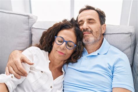 Man And Woman Couple Hugging Each Other Relaxed On Sofa At Home Stock