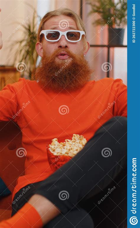 Man Sitting On Sofa Eating Popcorn And Watching Interesting Tv Serial