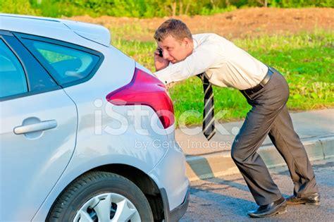 Businessman Pushing A Car And Talking On The Phone Stock Photo