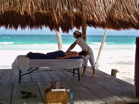 a woman getting a back massage on the beach under a thatched roof over
