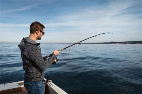 Man Fishing From A Boat In A Stock Photo Pixeltote