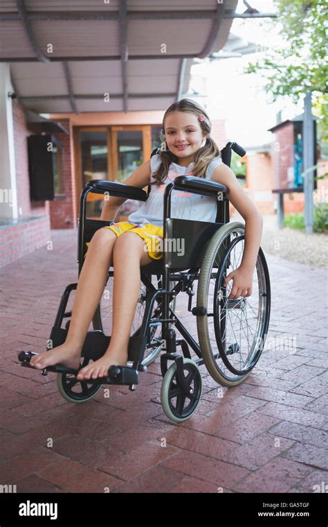 Portrait Of Cute Girl Sitting On Wheelchair In Corridor Stock Photo Alamy