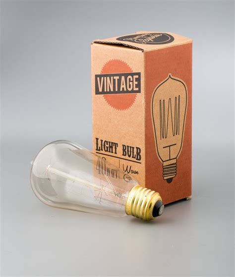 An Old Light Bulb Sits In Front Of A Cardboard Box On A Gray Surface