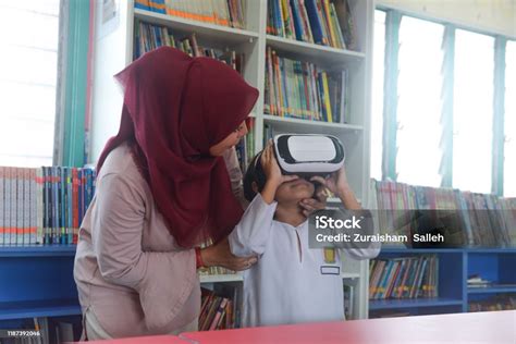 Asiatische Lehrerin In Hijab Hilft Ihrer Schülerin Mit Virtualrealitybrille Im Klassenzimmer