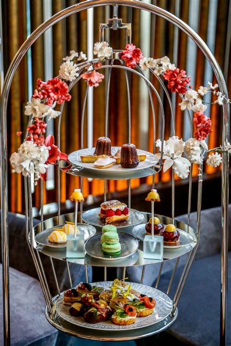 Three Tiered Trays Filled With Cakes And Pastries On Top Of A Table