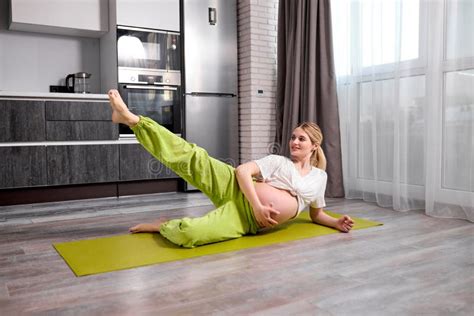 Junge Schwangere Frau Mit Nackten Bauch Heben Ein Bein Tun Übungen Auf Dem Boden Stockbild