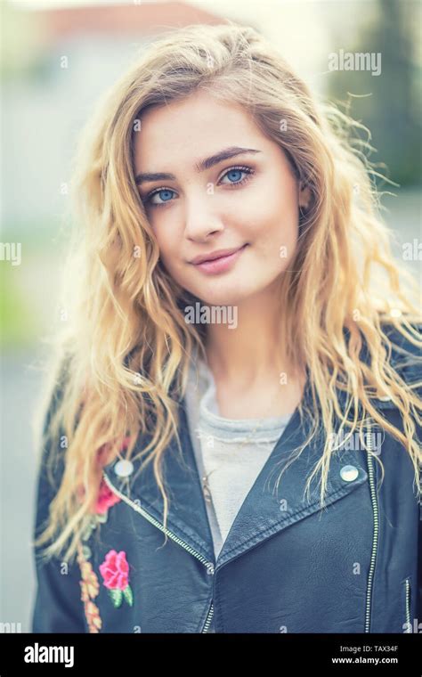 Portrait Of Attractive Blonde Girl With Curly Long Hair And Blue Eyes