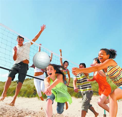 Group Of Teenage Friends Playing Volleyball On Beach Chippers Lanes