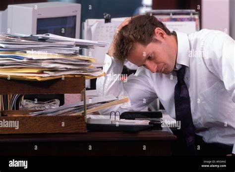 Stressed Male Office Worker Sitting At Desk With Piles Of Paperwork Stock Photo Alamy