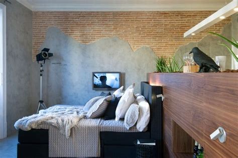 A Bedroom With A Bed Television And Brick Wall