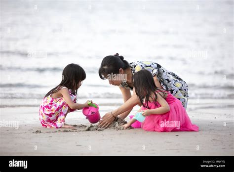 Asian Chinese Mum And Daughters Playing Sand Together At Beach Outdoor