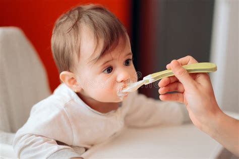 Funny Cute Adorable Baby Eating Yogurt In The Kitchen Stock Photo
