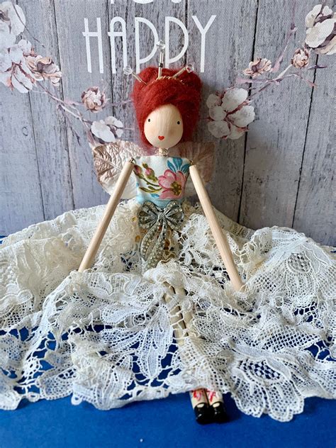 A Doll With Red Hair Sitting On Top Of A White Lace Doily Next To A