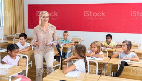 Woman Teacher Talking With Pupils At Classroom Stock Photo Download