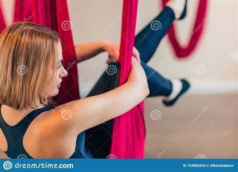 Woman Practices Anti Gravity Yoga On Red Hammock Indoor Close Up