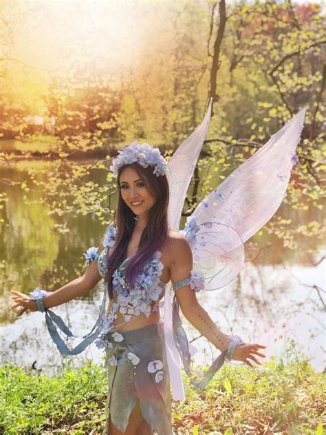A Woman Dressed As A Fairy Standing Next To A River