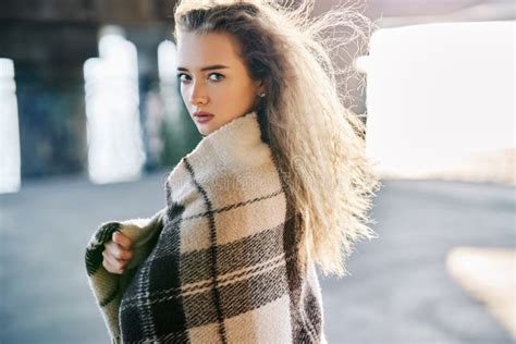 Beautiful Young Woman Portrait Wrapped In Wool Blanket Looking To Camera On Windy Sunny Day On