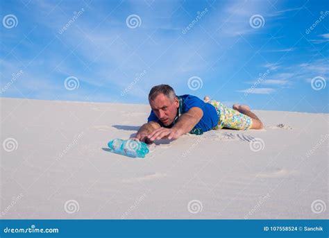 Man Lost In The Desert Reaches For The Bottle Of Water Stock Photo