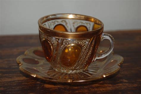 A Glass Cup And Saucer Sitting On Top Of A Wooden Table