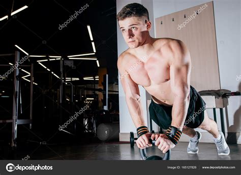 Strong Handsome Man Doing Push Ups On Dumbbells In A Gym As