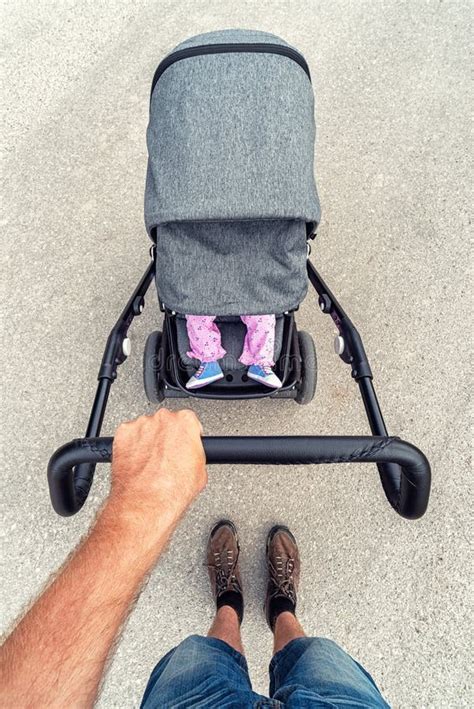 Legs Of Infant In Baby Stroller On Road Father With Pram Stock Image