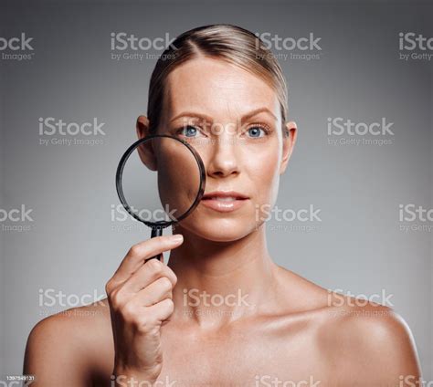Beautiful Mature Woman Posing With Magnifying Glass In Studio Against A