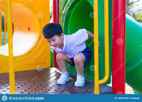 Asian Kid Playing Slide At The Playground Under The Sunlight In Summer