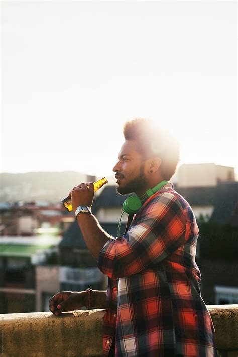 Side View Of A Young African American Man Drinking A Beer On A Terrace